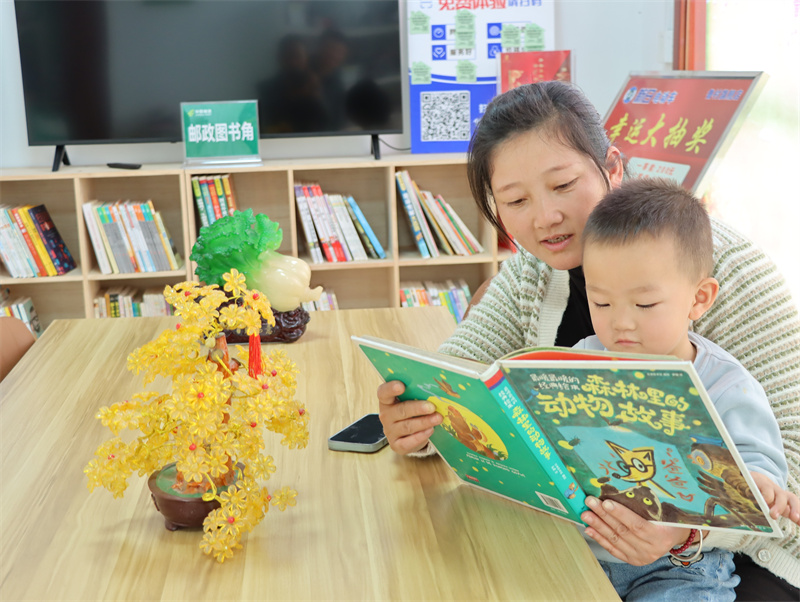 图为村民带着孩子在雪颖超市的图书角读书